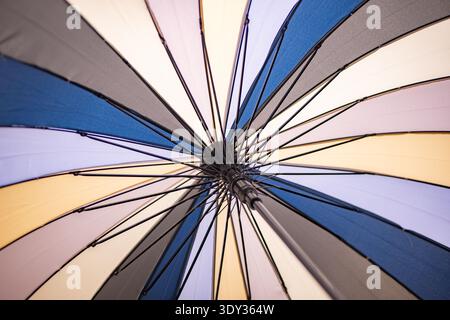 Multicolored umbrella opening, vibrant pattern and symmetry from a low angle Stock Photo