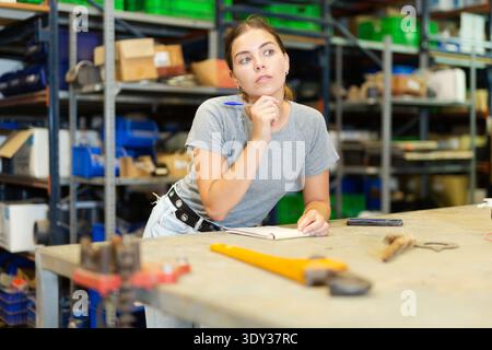 Portrait of thoughtful young woman worker checking order list Stock Photo