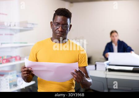Employee of printing house checks the quality of printing in computer room Stock Photo