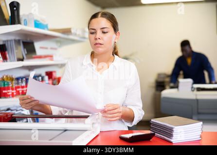 Portrait of an attentive woman checking quality of printing in printing house Stock Photo