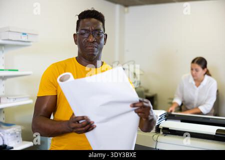 Technician african american working of printing house with stack of notebooks in her hands Stock Photo