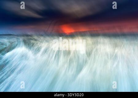 An ethereal and artistic abstract photograph depicting a seascape or waterscape during sunset or sunrise, created with intentional camera movement and Stock Photo