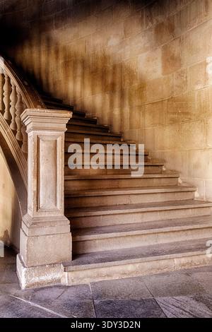 A mysterious grand staircase leads upwards into the darkness of the second floor of a building. Stock Photo