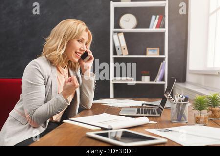Smiling businesswoman at work talking on phone Stock Photo