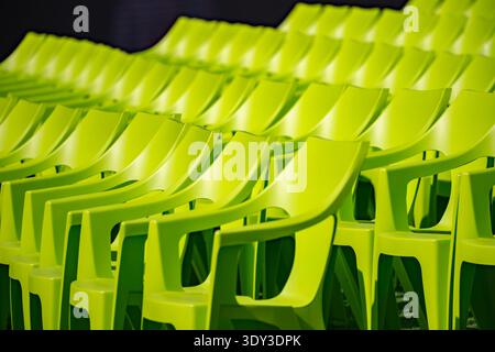 Bright green plastic chairs arranged in rows creating repetition and pattern Stock Photo