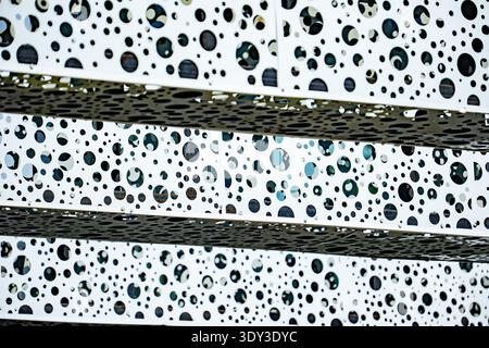 Modern building facade creating abstract pattern with multiple perforated circles Stock Photo