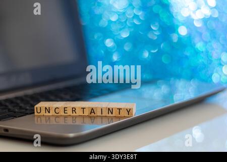 Uncertainty financial and forward-looking future business concept with wooden blocks on laptop silver blue bokeh copy space Stock Photo