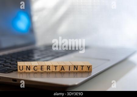 Uncertainty financial and forward-looking future business concept with wooden blocks on laptop silver blue bokeh copy space Stock Photo