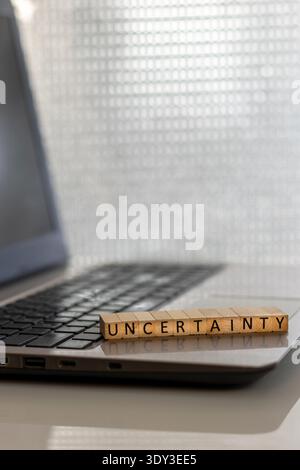 Uncertainty financial and forward-looking future business concept with wooden blocks on laptop silver blue bokeh copy space Stock Photo