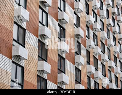 Modern residential building facade with many windows and external air conditioners Stock Photo