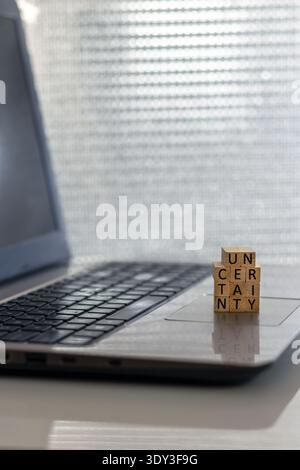Uncertainty financial and forward-looking future business concept with wooden blocks on laptop silver blue bokeh copy space Stock Photo