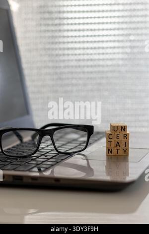 Uncertainty financial and forward-looking future business concept with wooden blocks on laptop silver blue bokeh copy space Stock Photo