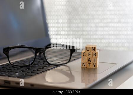 Uncertainty financial and forward-looking future business concept with wooden blocks on laptop silver blue bokeh copy space Stock Photo