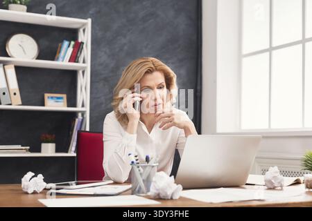 Serious business woman at work talking on phone Stock Photo