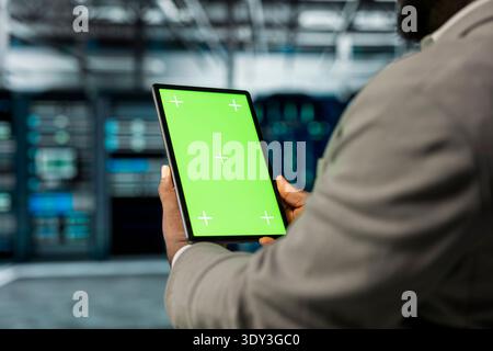 Close up of technician using isolated screen tablet in data center, monitoring performance using automation tools. Server hub employee using mockup device, troubleshooting connectivity issues Stock Photo