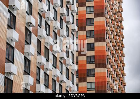 Modern residential building facade featuring colorful brick patterns and many air conditioners Stock Photo