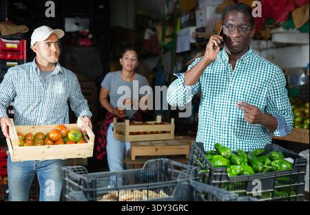 Man talking on phone in vegetable warehouse Stock Photo
