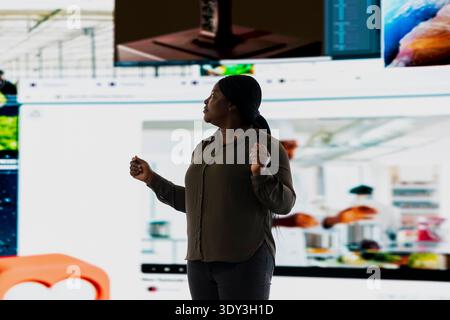 Person uses streaming service to look at online video content during leisure time in modern digital environment. Woman browses social media app projected on digital backdrop displaying clips collage Stock Photo