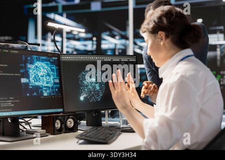 Data center team of admins doing brainstorming, using artificial intelligence neural networks tech. Server farm teamworking colleagues using AI programming language on computer to update equipment Stock Photo