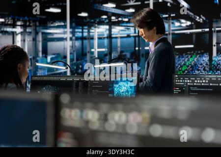 Data center system administrators adjusting AI model parameters to enhance accuracy. Server farm IT experts scheduling artificial intelligence ran maintenance for hardware components Stock Photo