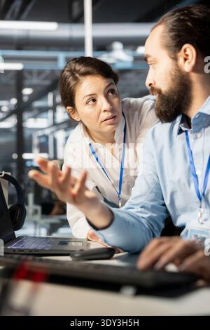 Team of admins talking in server hub, analyzing data. Data center office IT specialists doing brainstorming, examining supercomputers equipment, ensuring system integrity and security Stock Photo