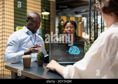 IT specialists using laptop in company conference room, implementing AI solutions to increase productivity. Engineers discussing artificial intelligence software development roadmap in startup office Stock Photo