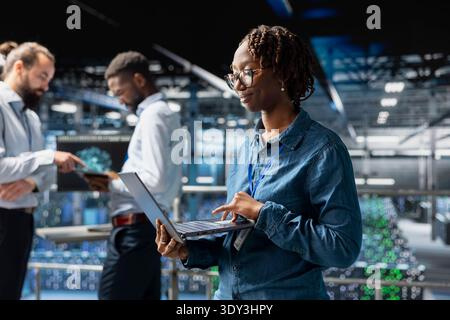 Confident black data scientist in server hub monitoring AI LLM visualization, neural network systems. Data center engineer brainstorming ideas to develop software with machine learning. Stock Photo