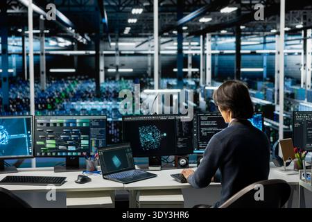 Data center computer scientist running simulations for AI driven forecasting, tracking performance. Server hub IT professional integrating machine learning APIs into software platforms Stock Photo