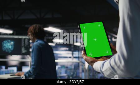 Data center engineers on industrial platform using isolated screen device, collaborating on tasks. Server hub workers visualizing large language model architecture using chroma key tablet Stock Photo