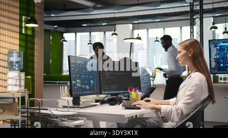 Pleased supervisor recognizing junior dev achievements at work, fostering positive office culture. Cheerful african american manager praising code written by female engineer, doing high five, camera A Stock Photo