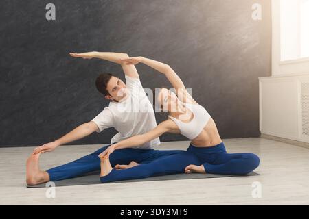 Young couple practicing yoga together in gym Stock Photo