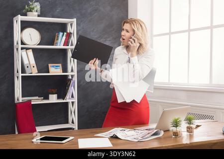 Angry businesswoman at work talking on phone Stock Photo