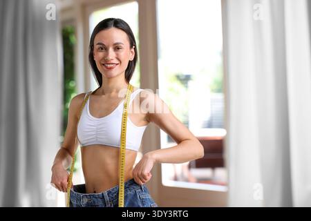 Happy woman in her old jeans showing weight loss result at home Stock Photo