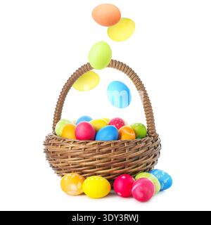 Bright Easter eggs falling into basket on white background Stock Photo