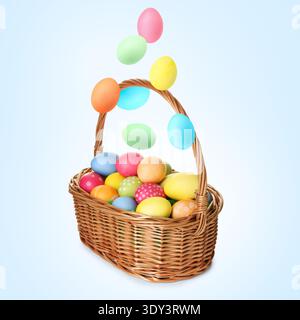 Color Easter eggs falling into basket on light blue gradient background Stock Photo
