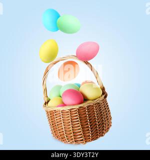 Color Easter eggs falling into basket on light blue gradient background Stock Photo