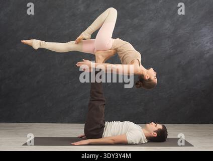 Young couple practicing acroyoga on mat together Stock Photo