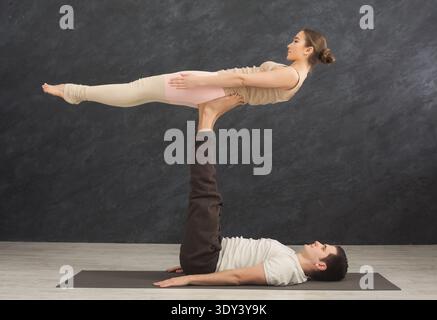 Young couple practicing acroyoga on mat together Stock Photo