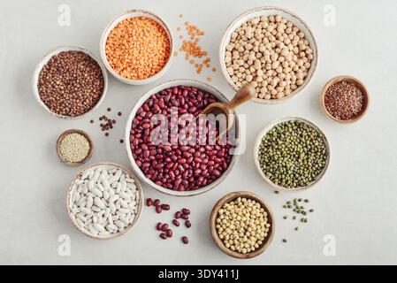 Various legumes, lentils, chickpeas, and beans in different bowls on a light background. Top view. Stock Photo