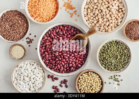 Various legumes, lentils, chickpeas, and beans in different bowls on a light background. Top view. Stock Photo