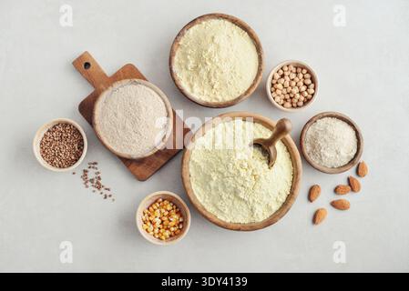 Wooden bowls with different types of gluten free flour and ingredients on light background, top view Stock Photo
