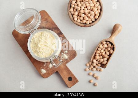 Chickpeas flour in glass jar with raw chickpeas on light background, top view Stock Photo