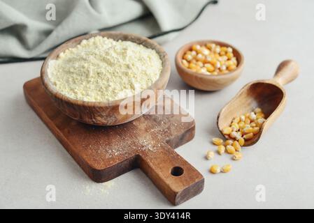 Corn flour in wooden bowl with raw corn on light background, closeup Stock Photo