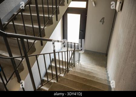 Concrete staircase leading down to a doorway in an old apartment building Stock Photo