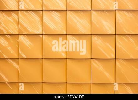 Yellow glossy ceramic tile wall with square pattern and light reflections Stock Photo
