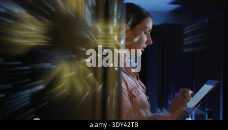Using tablet, tech in pink shirt wearing badge tapping screen in server aisle, copy space Stock Photo