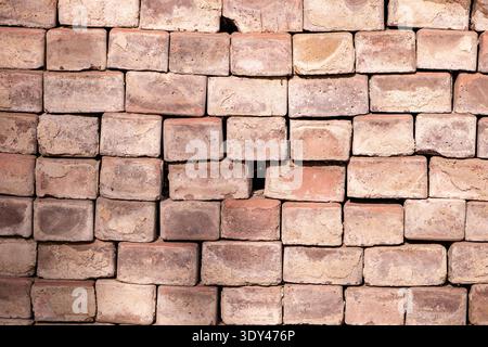 Stacked weathered common bricks forming a textured wall or pavement background Stock Photo