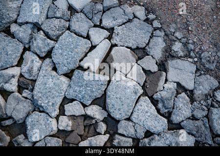 Broken asphalt pavement fragments creating a textured surface background Stock Photo