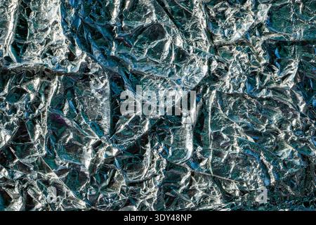 Crumpled aluminum foil surface creating a shiny silver and blue abstract background Stock Photo
