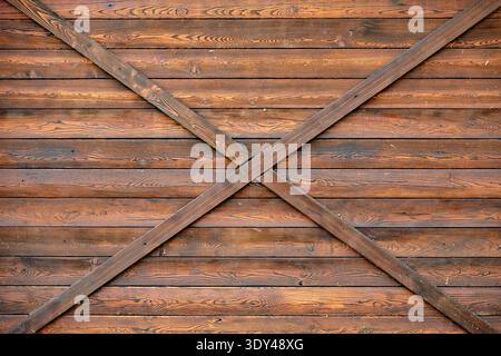 Rustic brown wood paneling creating an X pattern on a barn door texture Stock Photo